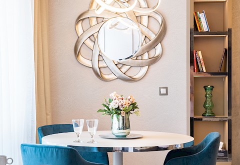 Výrazným prvkem u jídelního stolu je designové zrcadlo, které připomíná slunce. Motivem interiéru je moře, které mají majitelé rádi. Zvlněné prvky tento motiv umocňují.