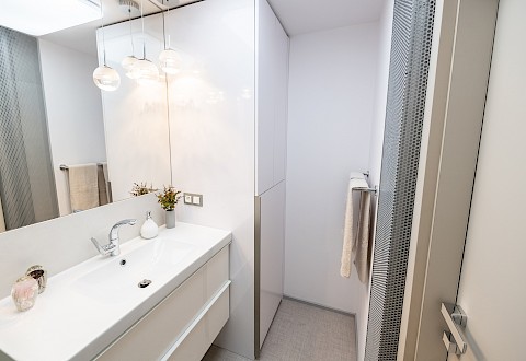 Výrazné topenářské stupačky v koupelně jsou kryty stříbrným děrovaným plechem a nenarušují jemnost celého prostoru.